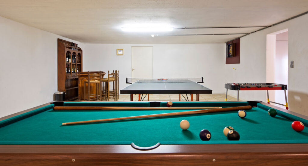 A newly remodeled basement with a pool and ping pong table.