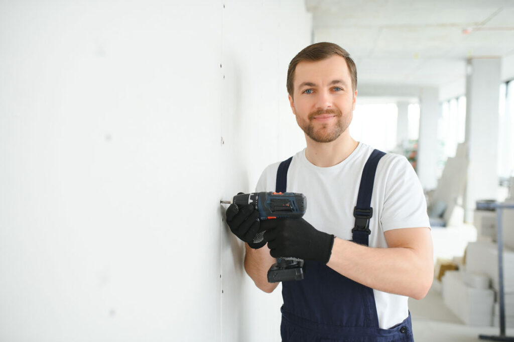 a person in overalls holding a drill